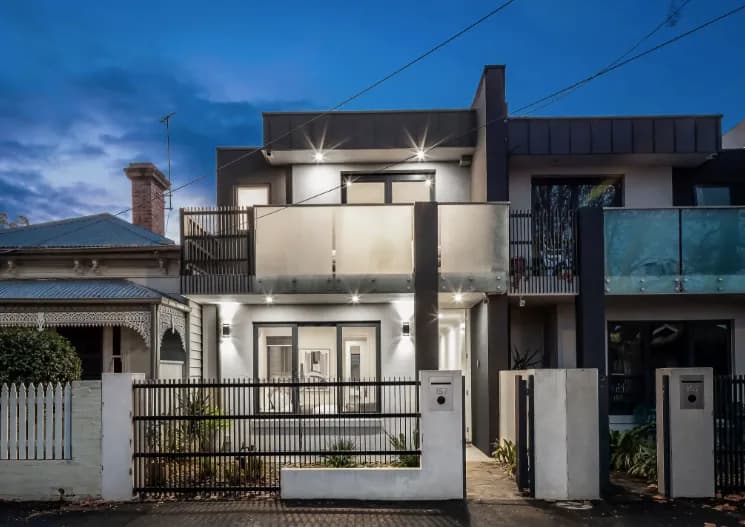 Modern narrow-block home facade at dusk by Nicon Built