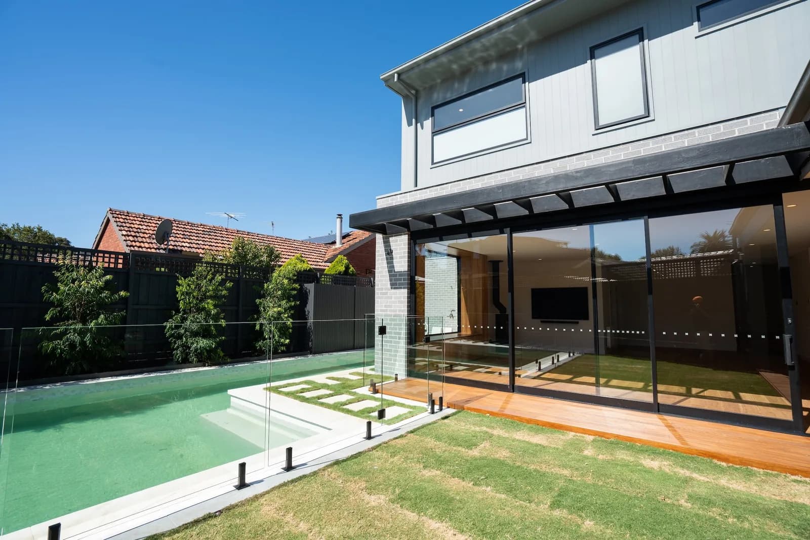 Modern rear extension with pool and glass fencing by Nicon Built