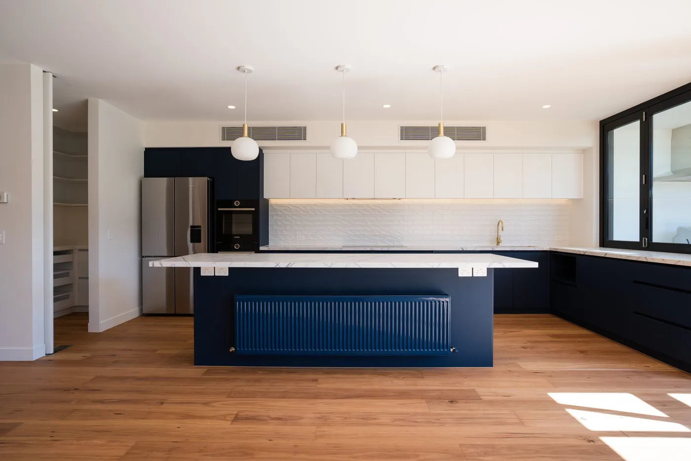 Navy kitchen with marble benchtop and gold tapware — Nicon Built