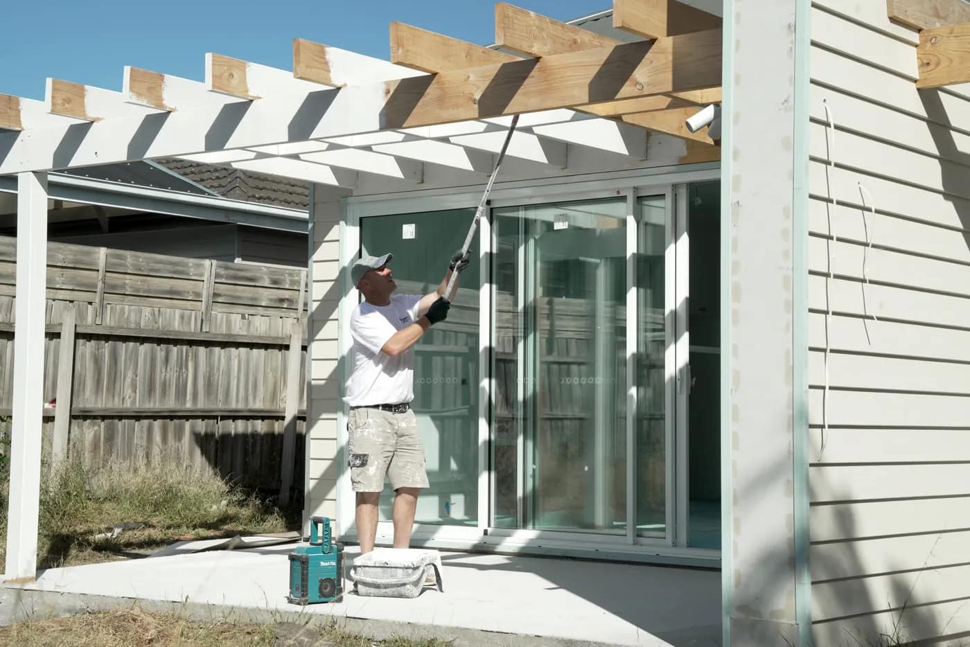 Builder painting pergola on site — Nicon Built